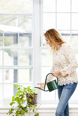 Smiling woman watering plant at home