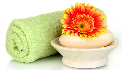 Rolled green towel, soap bar and beautiful flower isolated