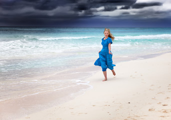 The woman in a long blue dress in a surf of  stormy sea..