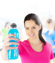 Happy young fitness woman holding bottle