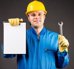 Portrait of a young worker holding a blank clipboard and a wrenc