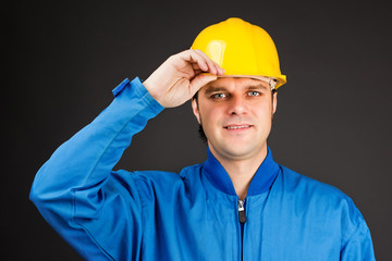 Young construction worker with his hand on hard hat brim