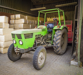Green tractor sheltered against the background of packages with