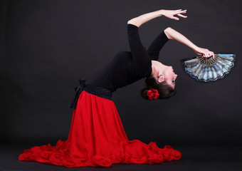 Attractive spanish young woman dancing flamenco over black backg