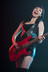 Obraz na płótnie Canvas Expressive young woman playing the electric guitar, studio shot
