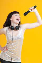 Expressive woman singing with a microphone, yellow background