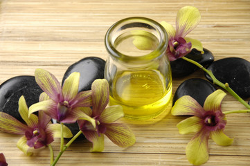 Massage oil and black stones with orchid in the spa