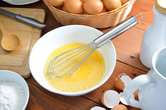 Eggs Yolk With Whisk On Wooden Table