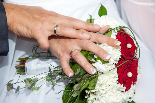 Hands with wedding rings and bridal bouquet
