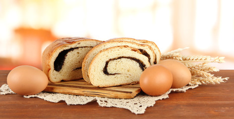 Loaf with poppy seed on cutting board, on bright background