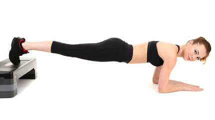 Obraz premium Young woman doing fitness exercises on stepper isolated on