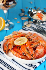 Shrimps with lemon on plate on wooden table close-up