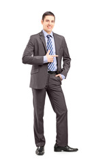 Full length portrait of a young businessman standing and pointin