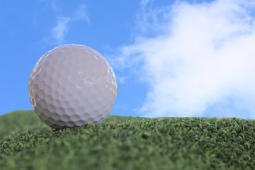 A golf ball on a green grass and a blue sky