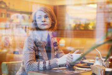 a young beautiful woman is drinking from a cup