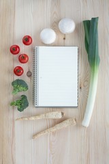 Empty notebook with vegetables on a wooden