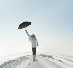 beautiful woman flying with umbrella on road in winter