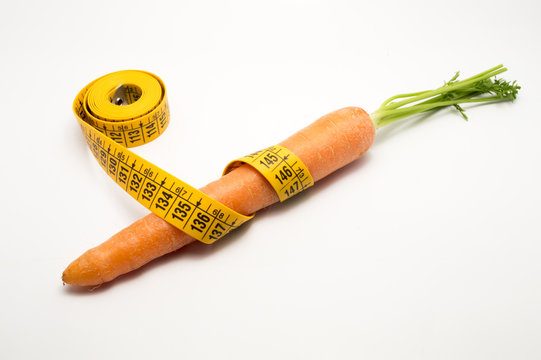 carrot with measuring tape around it in white background