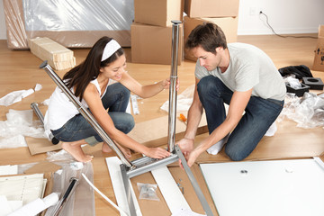 Couple moving in together assembling furniture table - obrazy, fototapety, plakaty