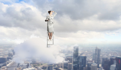 Businesswoman standing on ladder