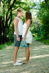 Young happy couple walking in green park holding hands