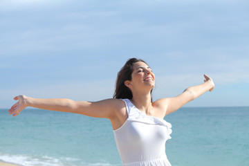Fototapeta na wymiar Beautiful girl with her arms raised on the beach