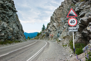 A sign by the road between two rocks, on a mountain pass
