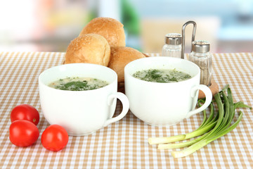 Fragrant soup in cups on table in kitchen
