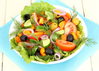Fresh salad in plate on wooden table