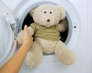 woman taking fluffy toy from washing machine