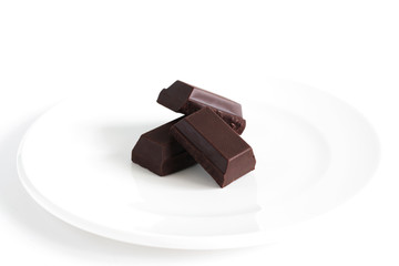 Dark chocolate block or bark on white plate, isolated