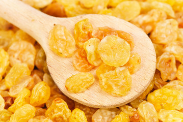 Golden raisins close- up and wooden spoon, food background