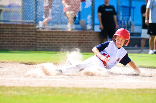 Little league baseball player sliding home.