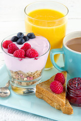 Closeup of breakfast with yoghurt, berries, juice, toast and cof