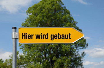 Fototapeta premium Gelber Pfeil mit Baum HIER WIRD GEBAUT
