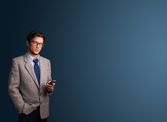 Young man standing and typing on her phone with copy space