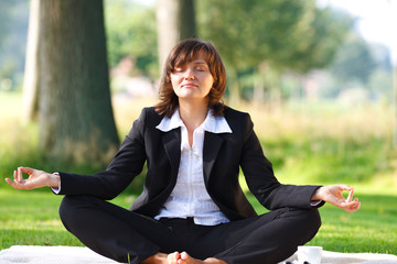 businesswoman meditating outdoor in park