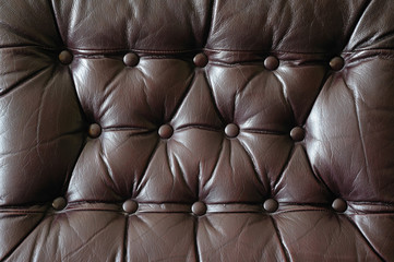 A detail of an old leather couch with big buttons 