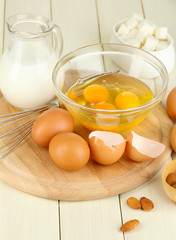 Broken egg in bowl and various ingredients next to them
