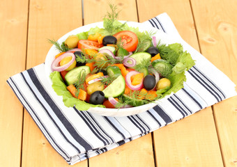 Fresh salad in plate on wooden table
