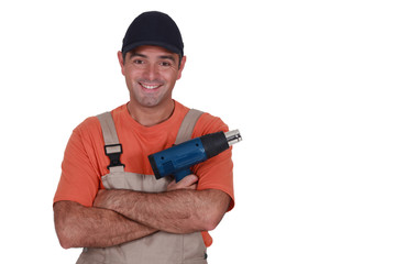 A male construction worker with a hot air blower.