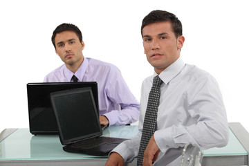 Fototapeta premium Two businessmen sat at the same desk
