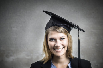 Junge blonde Studentin mit Absolventenhut.