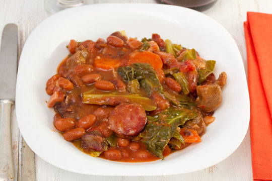 meat with sausages and vegetables on the white plate