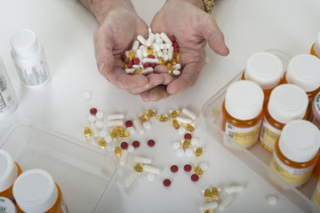 Hands holding pills surrounded by pill bottles