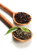 Dry tea with green leaves in wooden spoons, isolated on white