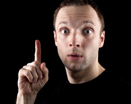 Surprised man with finger up idea gesture on black