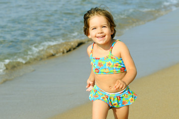 Happy toddler girl running at beach