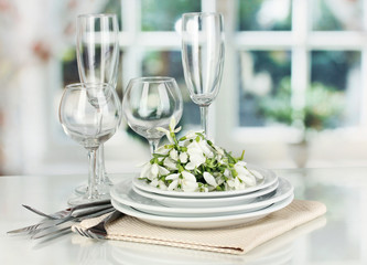 Serving dishes and snowdrops on room background