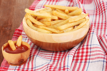 French fries in bowl on wooden table close-up